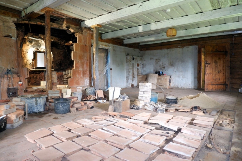 Restaurācijas procesā daļēji demontēta krāsns. Krāsns augšējā labā stūrī redzams dūmu kanāla izvads uz bēniņiem. M. Varbūta foto.