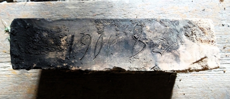 Krāsns iekšējā slānī atrastais ķieģelis ar zīmēm. E. Žīgura foto.