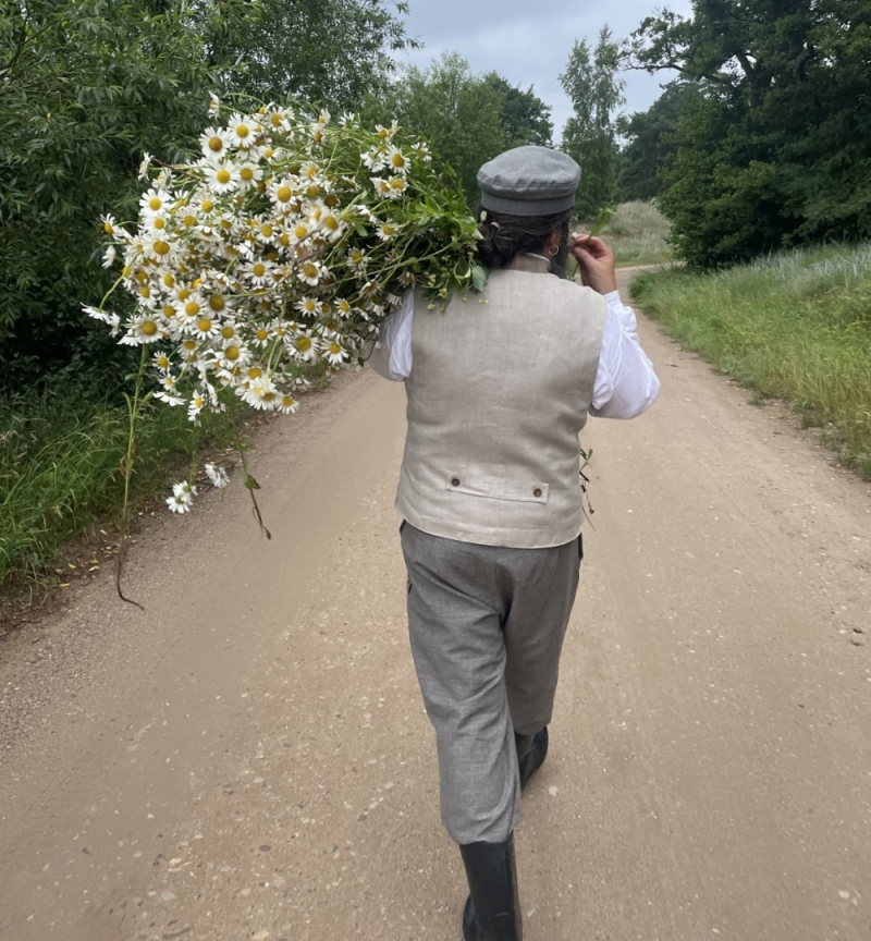 Līgotājs dodas pa ceļu ar ziedu pušķi rokās