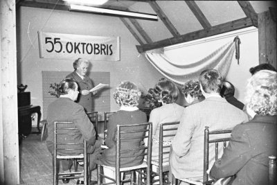 Vēsturiska sapulce; fonā baneris "55. oktobris".