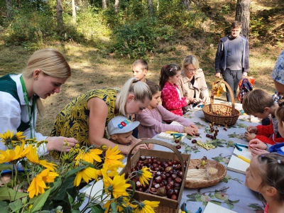 Bērni pie galda veido figūriņas no kastaņiem