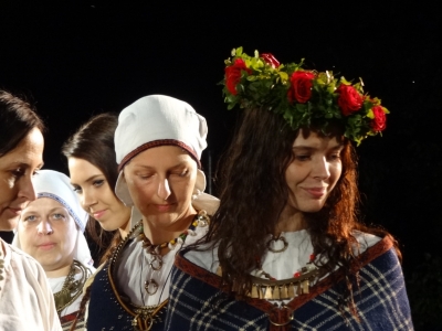 Jaunas meitenes tautastērpos ar krāšņiem rožu vainagiem galvā.
