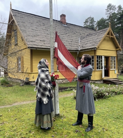 Jaunieši pie Jaunsaimniecības ēkas uzvelk Latvijas valsts karogu.