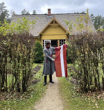 Puisis tautastērpā tur Latvijas valsts karogu.