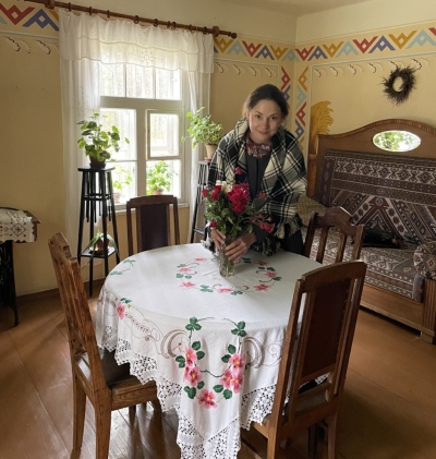 Meitene Jaunsaimniecības goda istabā liek vāzē sarkanbaltsarkanas rozes.