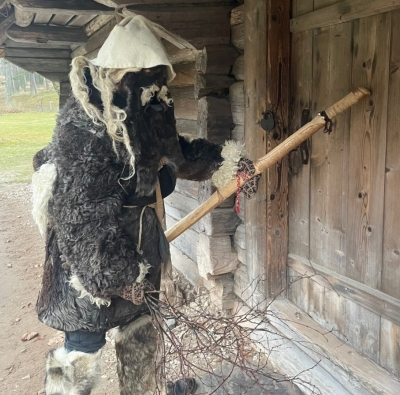 Mārtiņdienas maska kažokā un sejas maskā klauvē pie Vidzemes sētas durvīm.