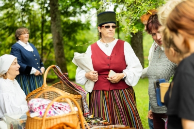 Sieviete tautastērpā rāda austas prievītes interesentiem
