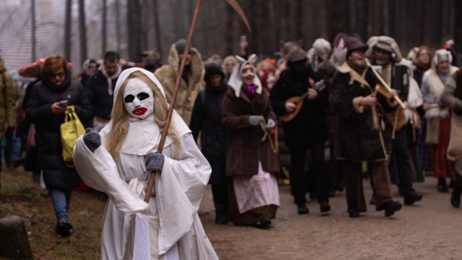 Masku gājiens Ziemassvētkos; priekšplānā dalībnieks tradicionālajā Nāves maskā. 