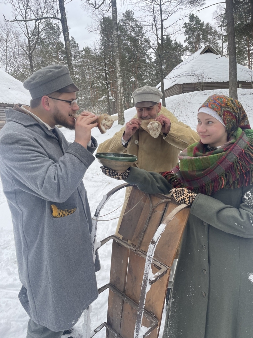 Jaunieši pie ragaviņām; puiši demonstrē tradicionālo mielastu – cūkas ausis