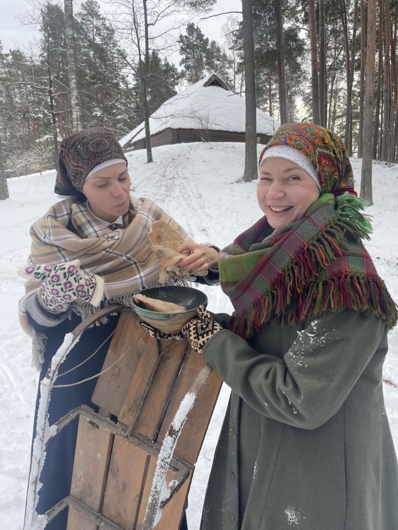 Divas priecīgas meitenes ar bļodu, kurā ir vārīta cūkas gaļa un ausis