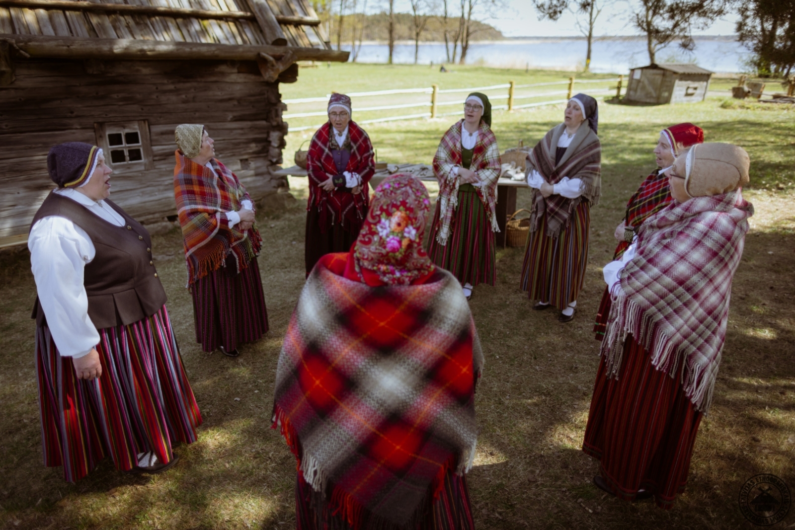 Sievietes tautastērpos stāv aplī muzeja Mauru sētas pagalmā un vienojas kopīgā dziesmā.
