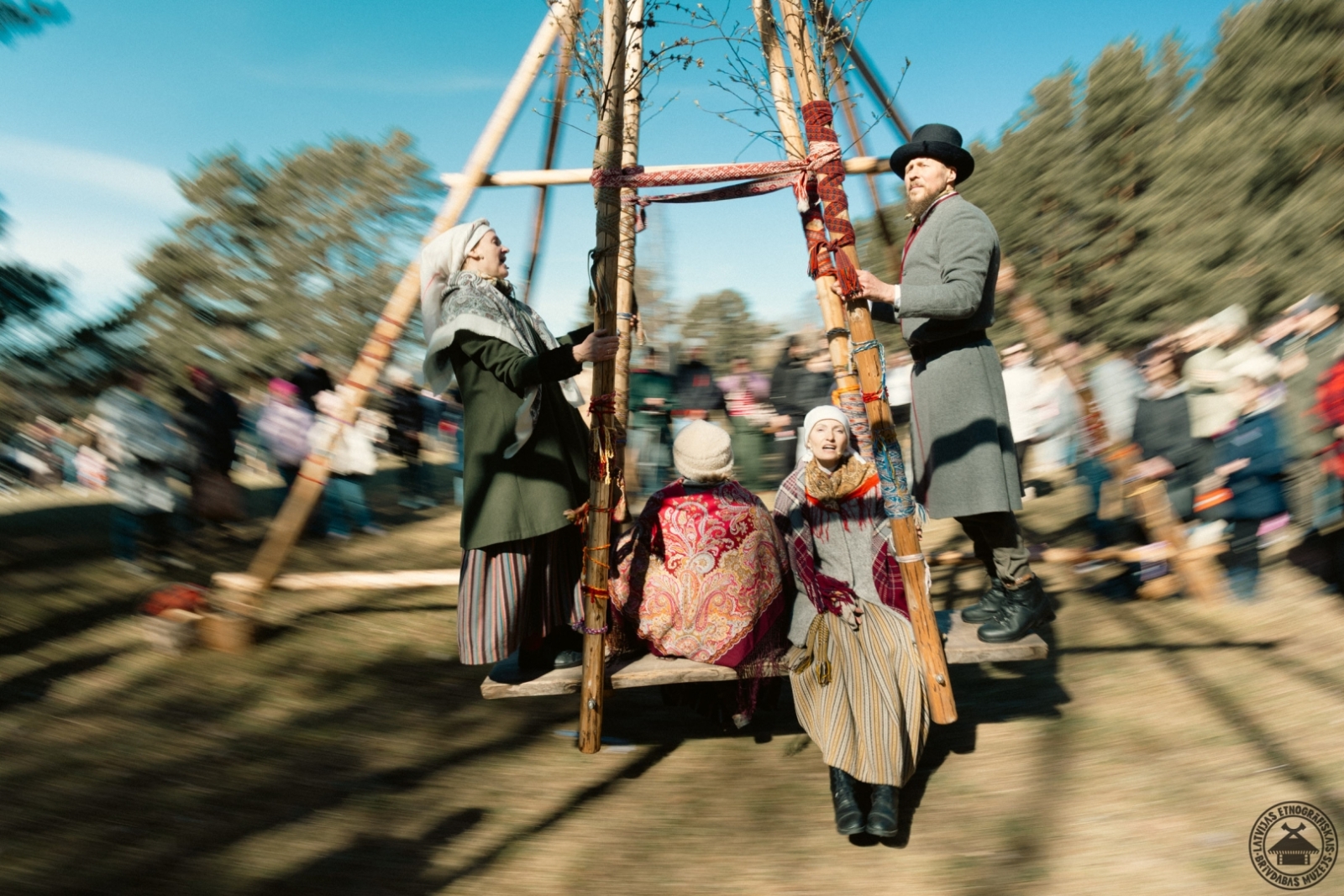 Cilvēki tradicionālajās Lieldienu svinībās šūpojas lielajās koka šūpolēs.