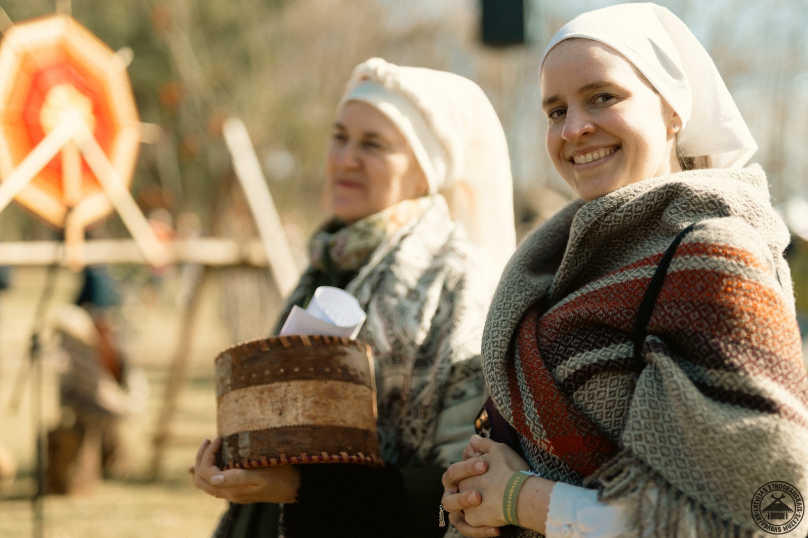 Divas smaidīgas un priecīgas sievietes greznos tautastērpos bauda Lieldienu svinības.