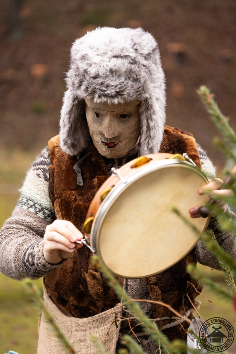 Dalībnieks maskā spēlē mandolīnu Ziemassvētku svinību laikā. 
