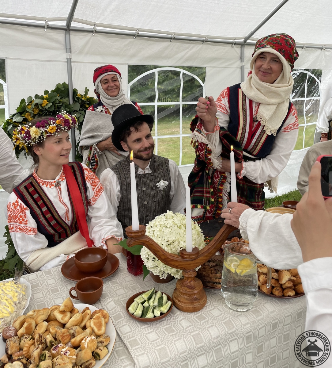 Svinīgs brīdis: jaunajam pārim pie goda galda tiek aizdedzinātas sveces greznā svečturī. 