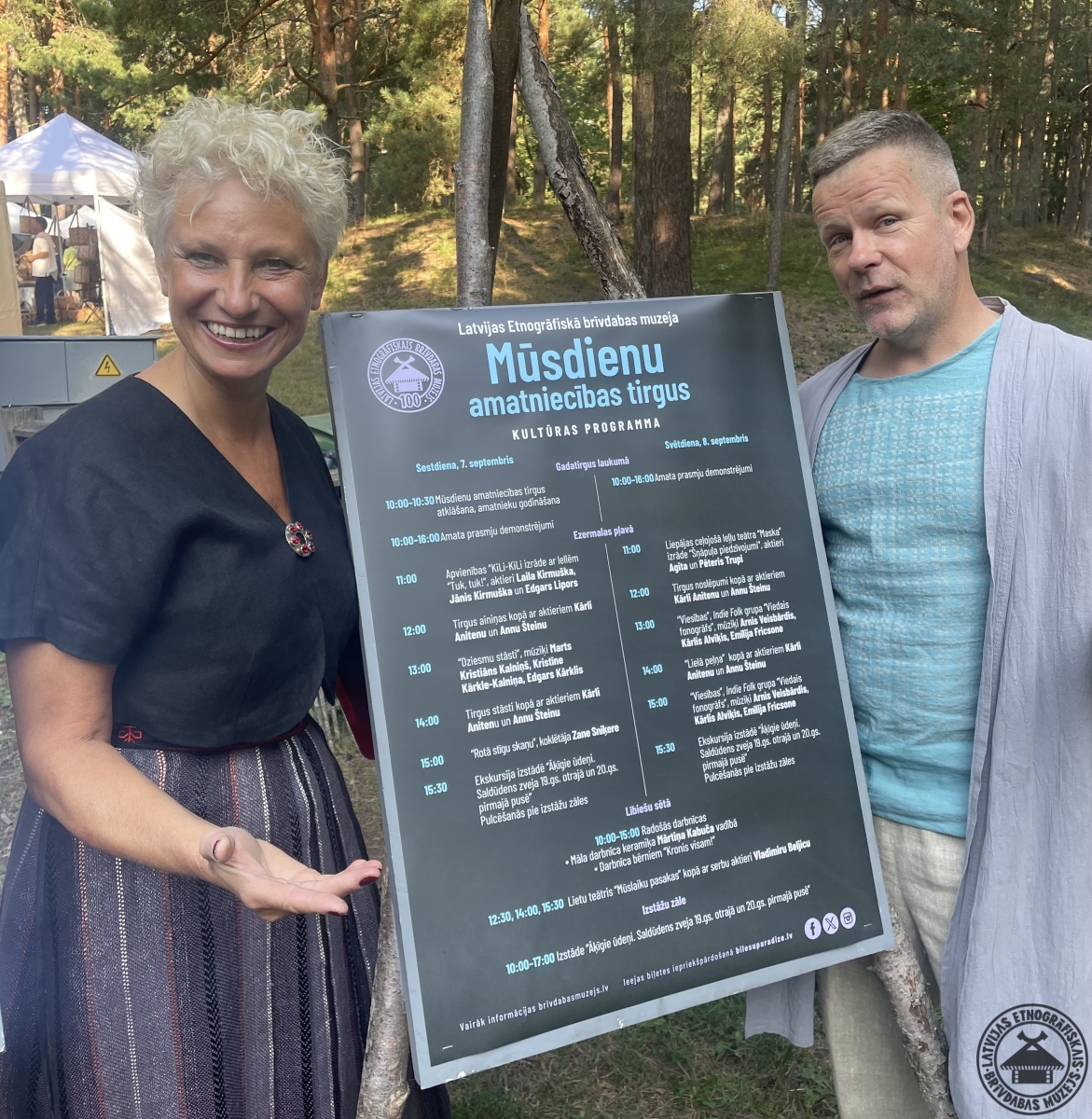 Kultūras programmas vadītāji pie stenda ar abu dienu svētku norises plānu. 