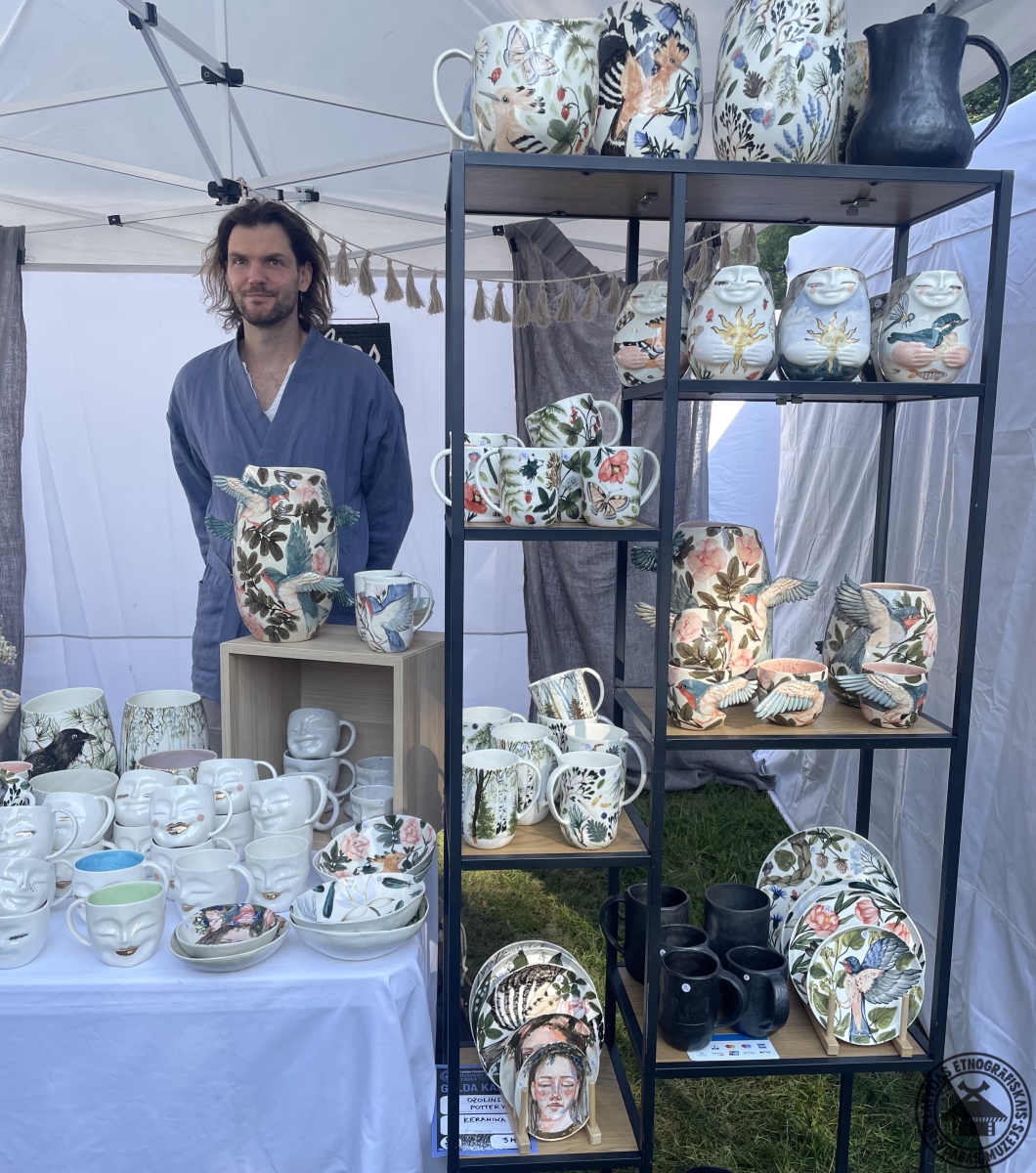Porcelāna meistars prezentē savas smalki apgleznotās kafijas tasītes, krūzes un šķīvjus. 