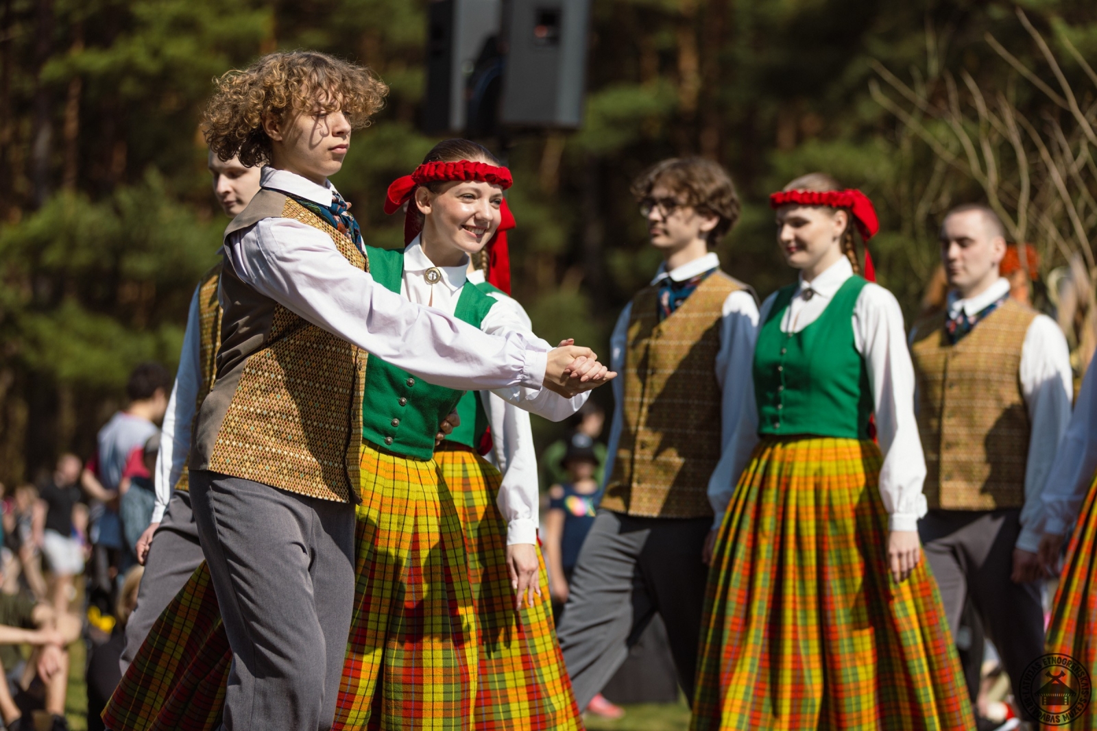 Jauniešu deju kolektīvs tautastērpos izpilda dinamisku latviešu tautas deju. 