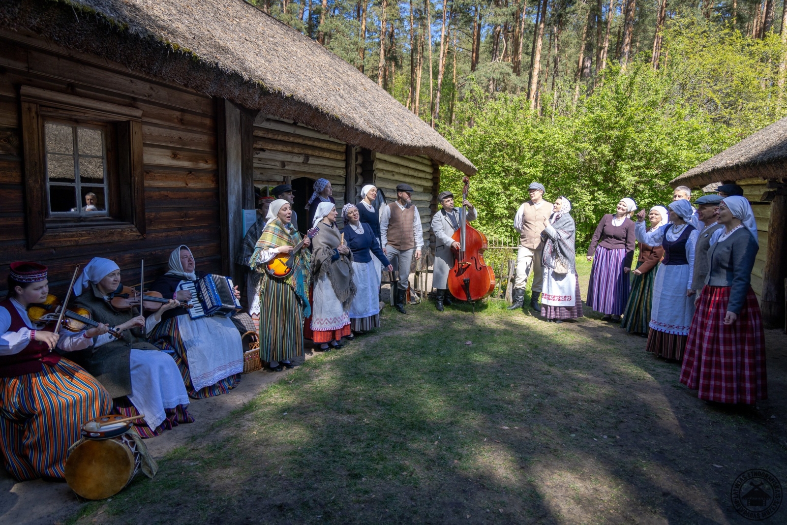 Aktieri un folkloras kopa Latgales sētā; visi tērpušies atbilstoši laikmetam un spēlē instrumentus. 