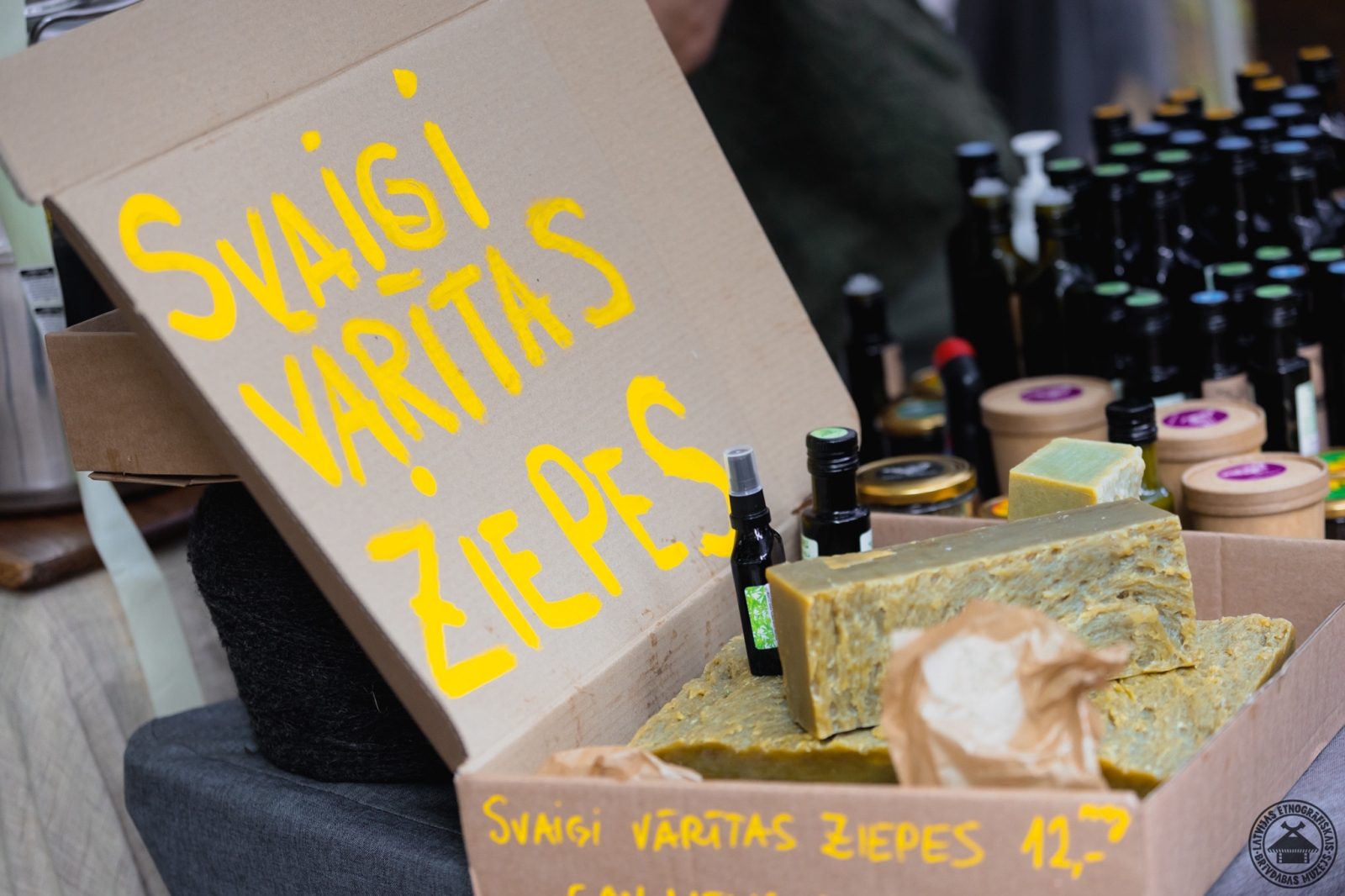 Tirdzniecības vieta ar kaņepju eļļu un ziepēm; redzams uzraksts “Svaigi vārītas ziepes”  