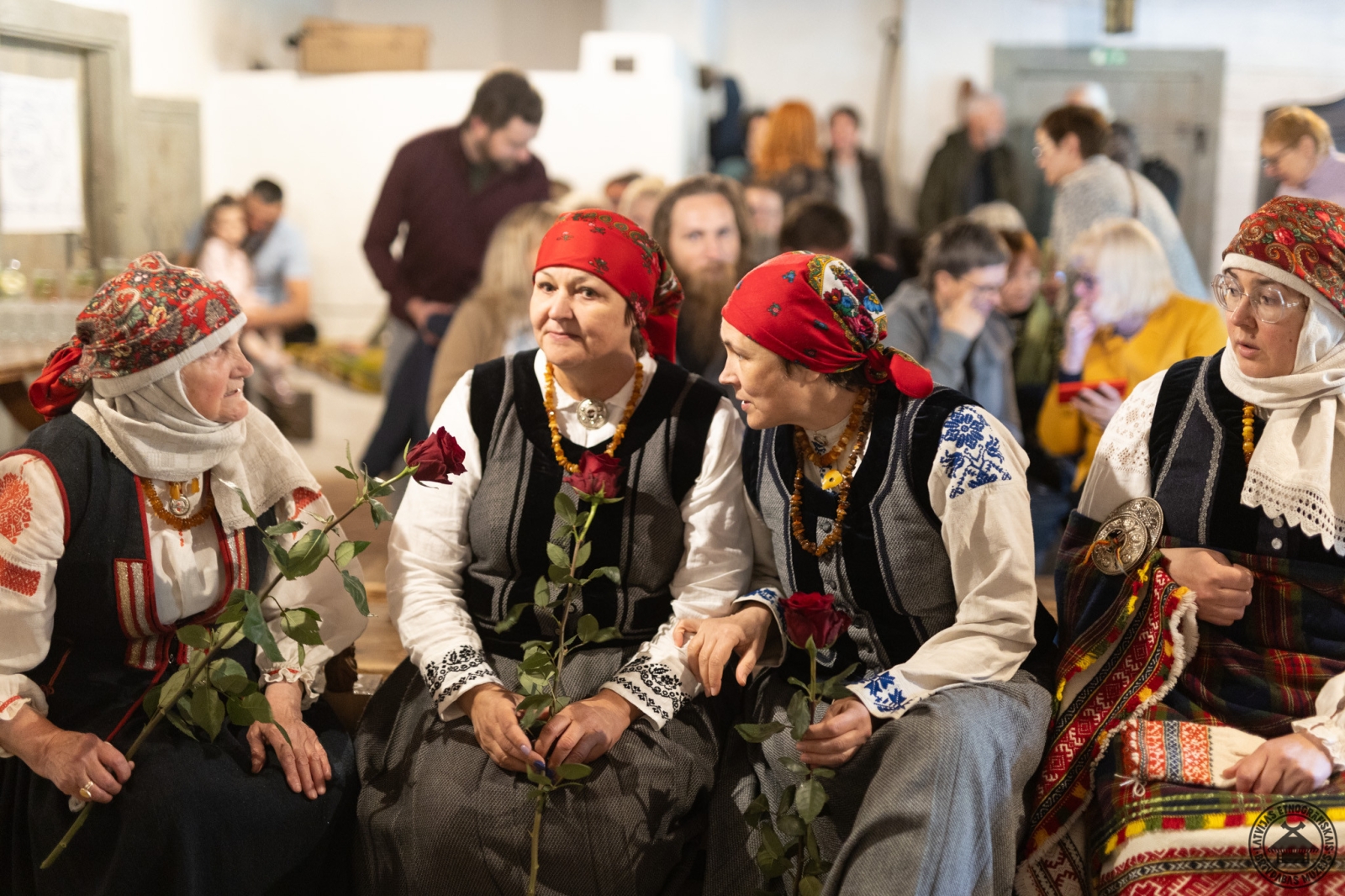 Izstādes atklāšanas mirklis: četras sievietes Rucavas tautastērpos ar rozēm rokās. 