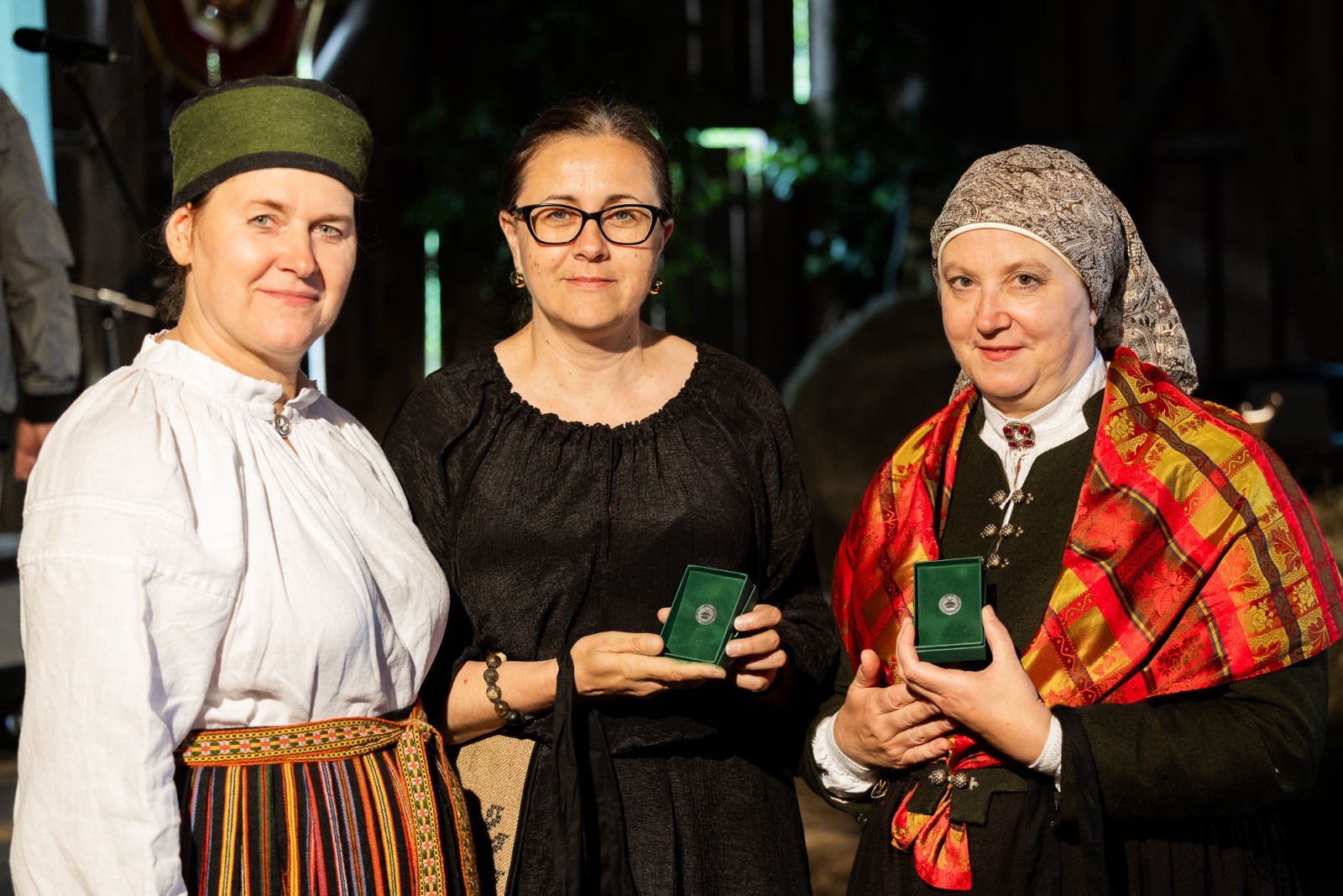 Trīs sievietes; divas no viņām lepni tur rokās tikko saņemtās muzeja goda zīmes. 
