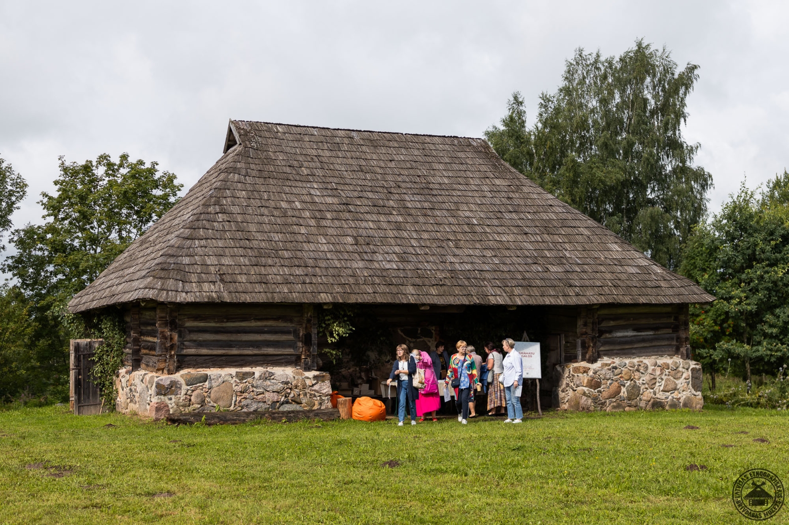 Apmeklētāju grupa pulcējas pie vēsturiskās Vēveru ratnīcas ēkas. 