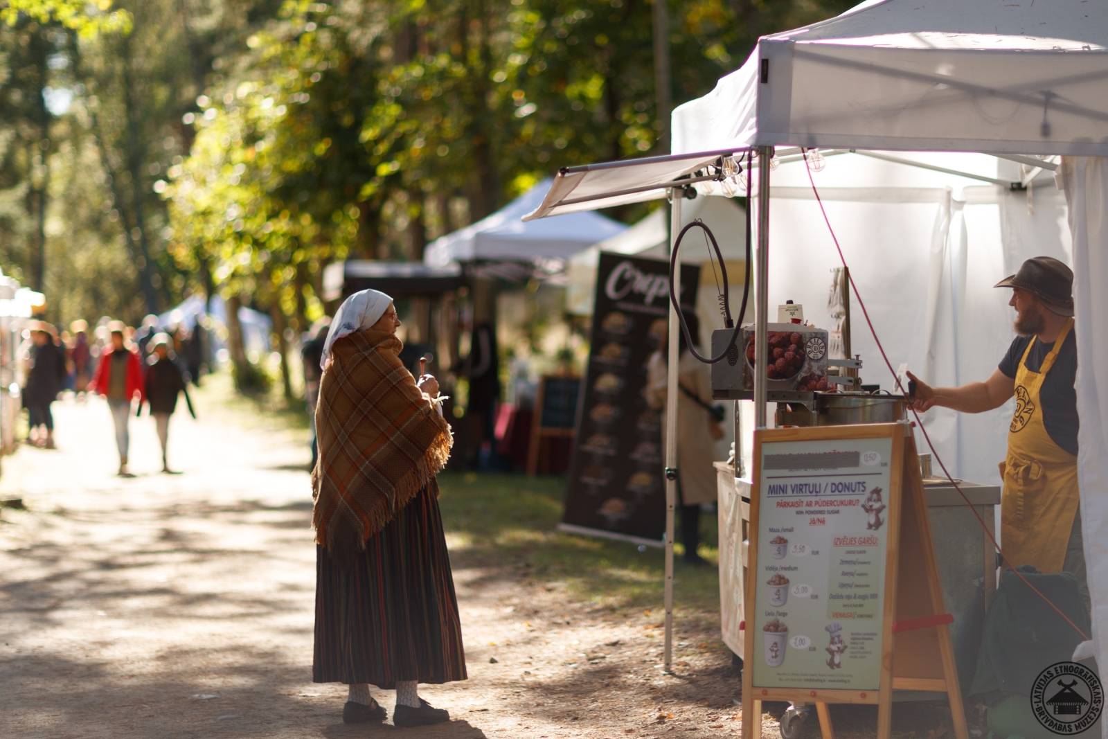 Sieviete tautastērpā dodas cauri bagātīgajam Miķeļdienas tirgus laukumam. 
