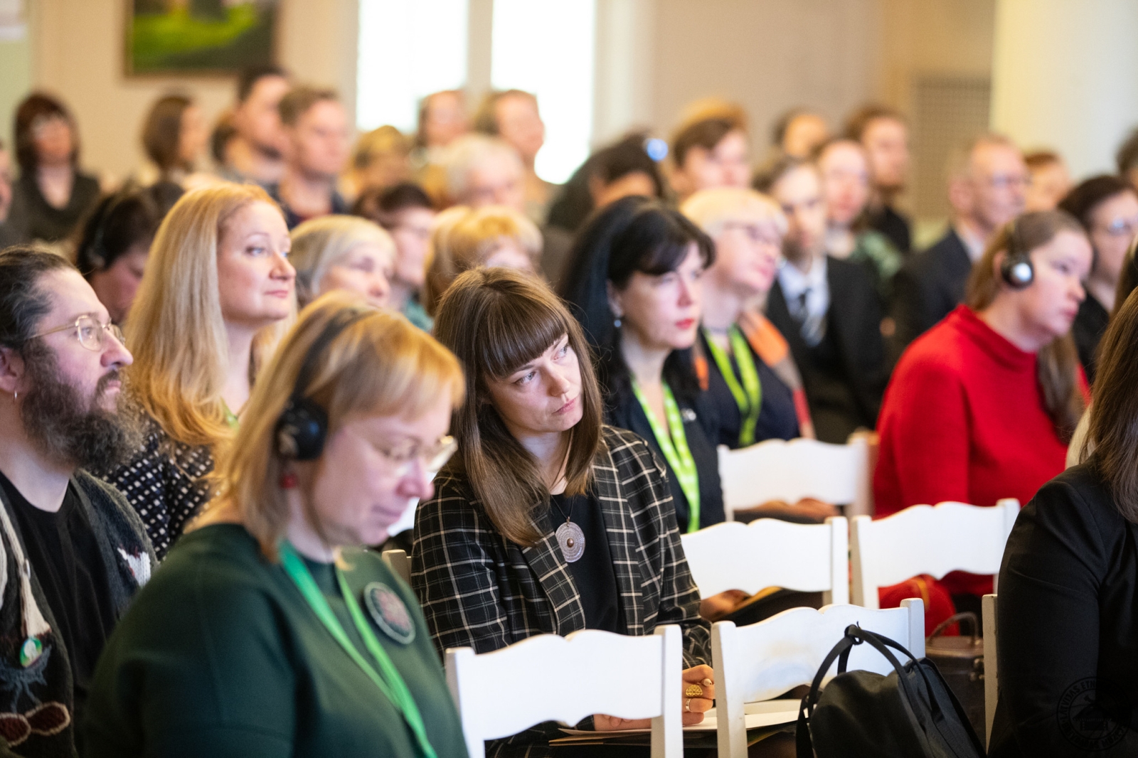 Skats uz konferences auditoriju; dalībnieki ieinteresēti vēro prezentācijas. 