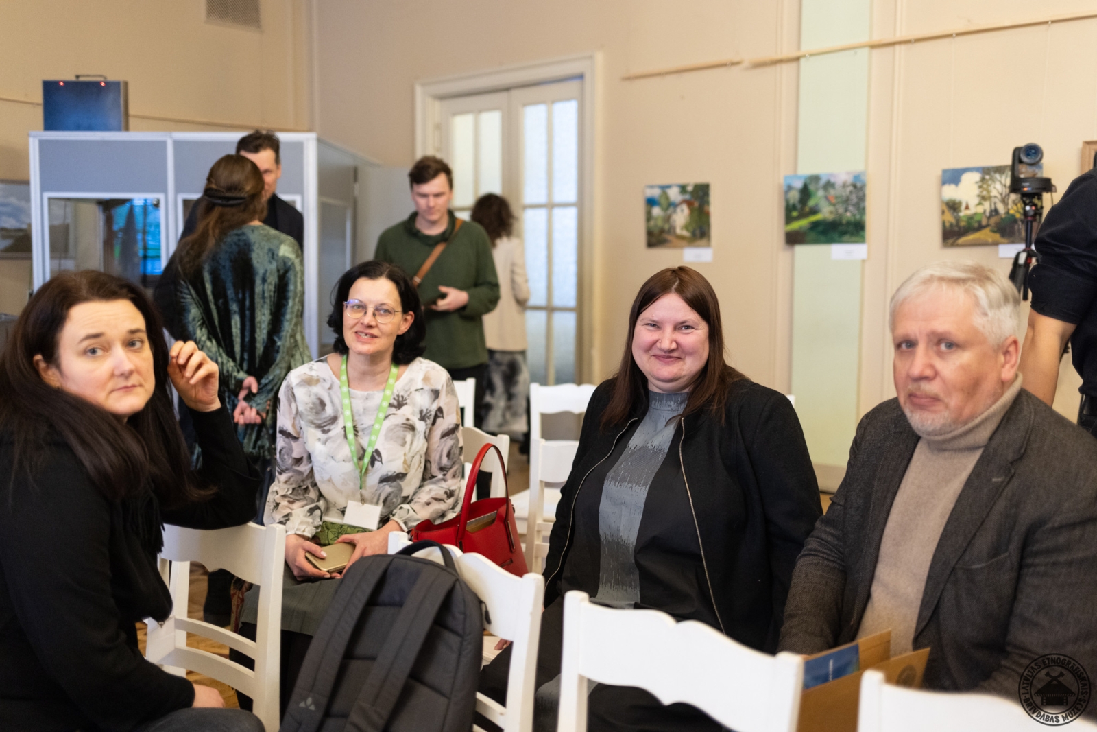 Konferences atpūtas brīdis; muzeja darbinieki neformālās sarunās pie kafijas. 