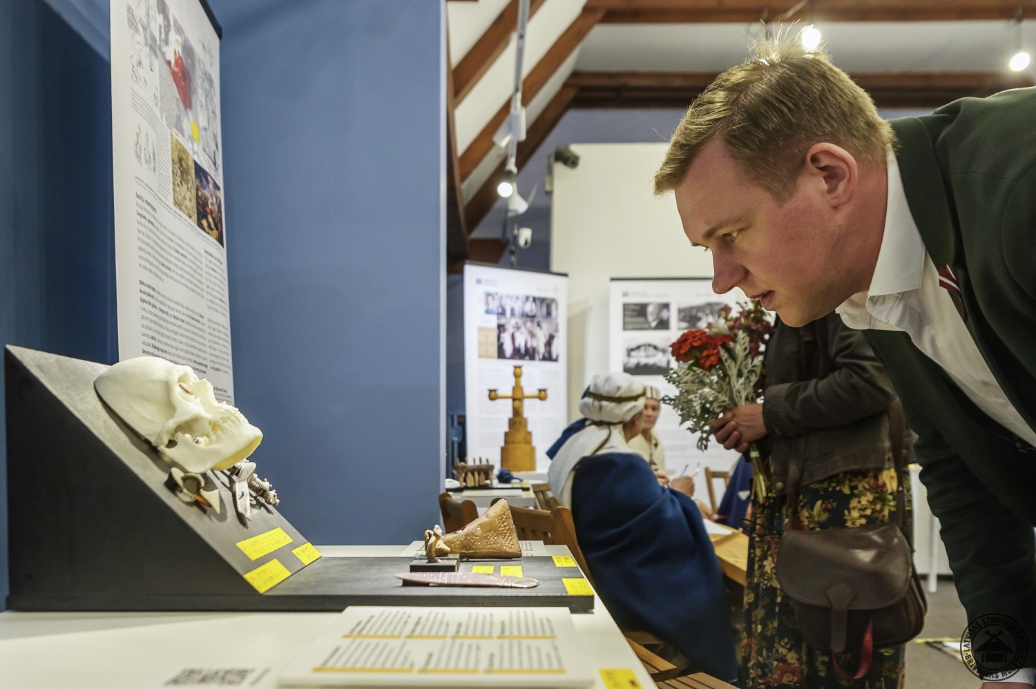 Vīrietis koncentrēti pēta izstādes informatīvos materiālus un objektus. 