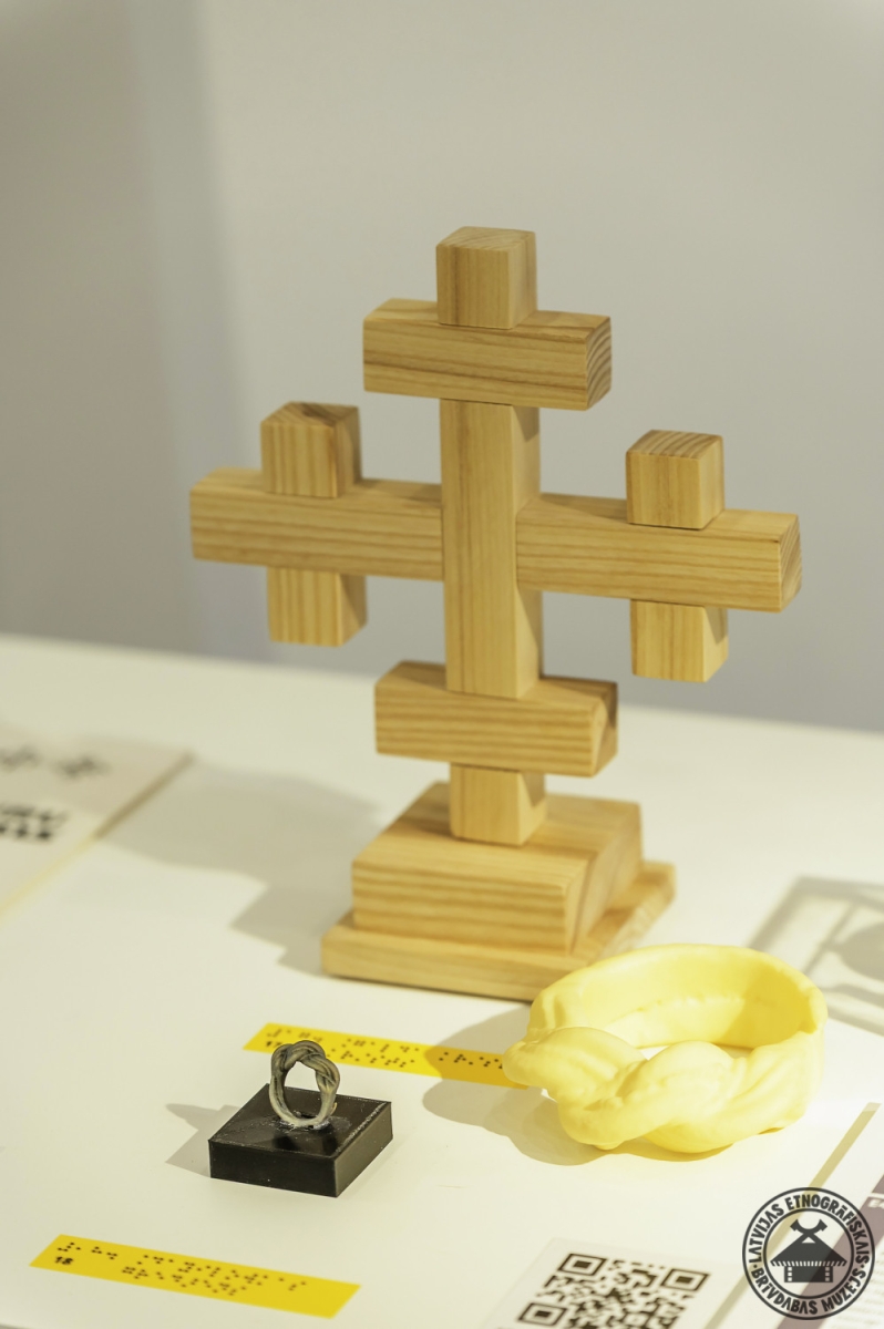 Izstādes eksponāti: koka Dievturu krusts un tradicionālais Nameja gredzens. 