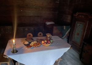 Vakarīga un mājīga noskaņa klētī, kur uz klāta galda līdzās tradicionālajam ēdienam deg svecīte veļu piemiņai.