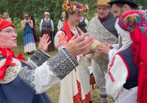 Jaunais pāris un kāzu viesi greznos Rucavas tautastērpos svin kāzas Annu dienā.